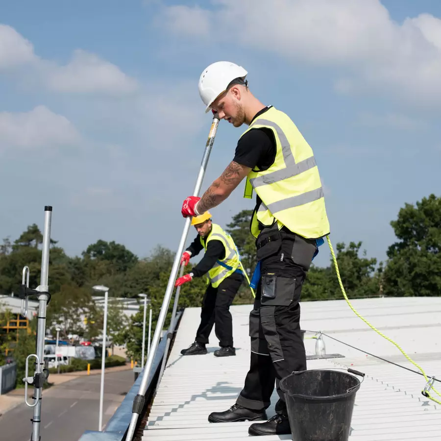 Workmen on roof cleaning gutter