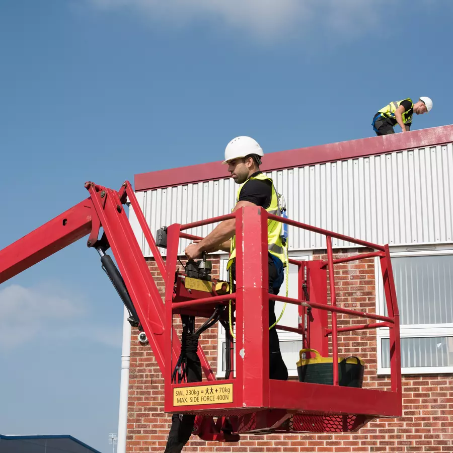 Workmen cleaning a roof with the aid of a roof lift