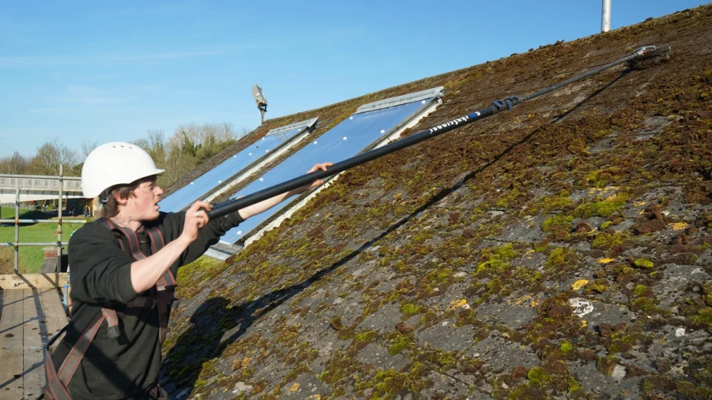 ben's gutters commercial cleaner scraping moss from a roof